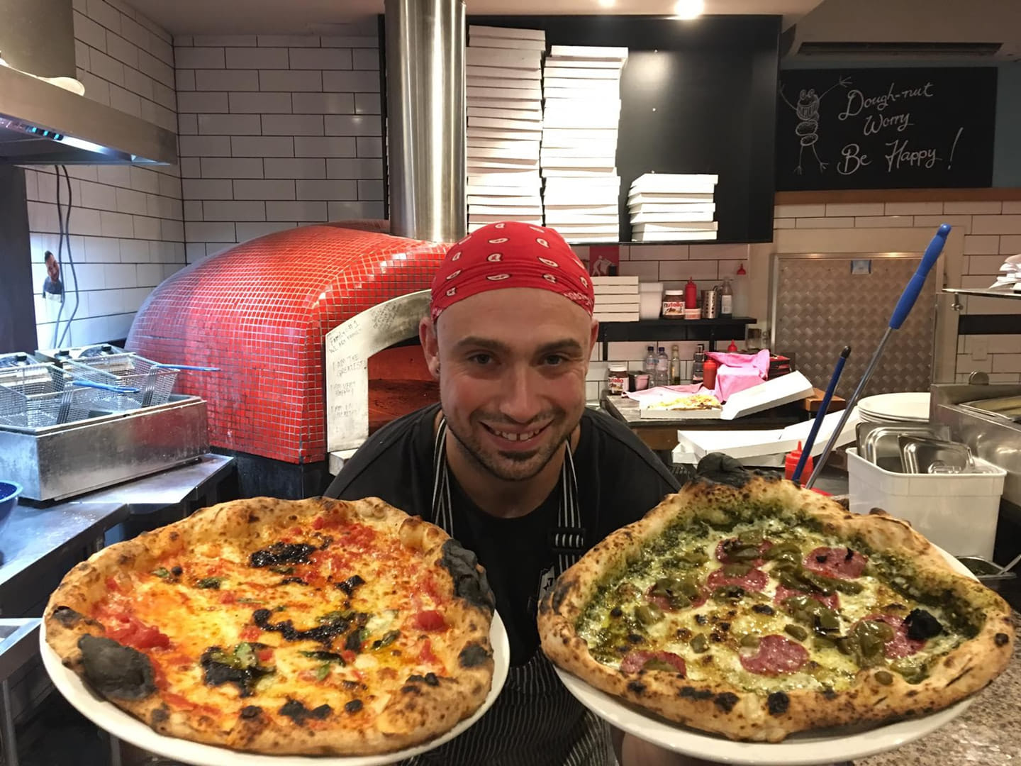 Micheluccio holding up freshly made pizzas